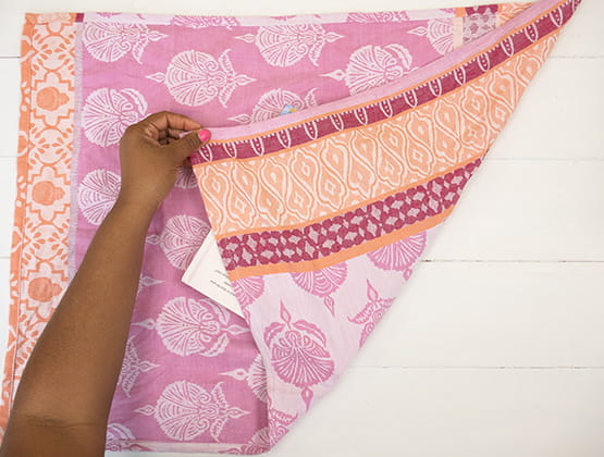 P-touch embellish craft step 2: Person wrapping square gift with bottom corner of tea towel