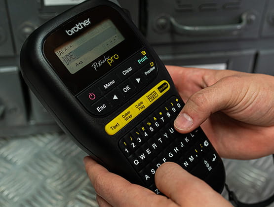 Brother Ptouch Pro handheld device with hands typing on built in keyboard