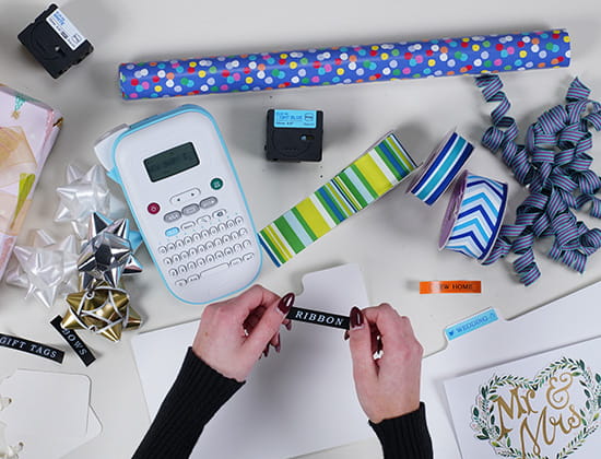 Brother Ptouch with Label Tape and Gift wrapping equipment around, a person labeling close to a folder