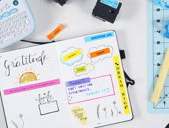 A gratitude journal in progress with colorful labels like "sunshine" and "coffee" on a table with crafting tools.