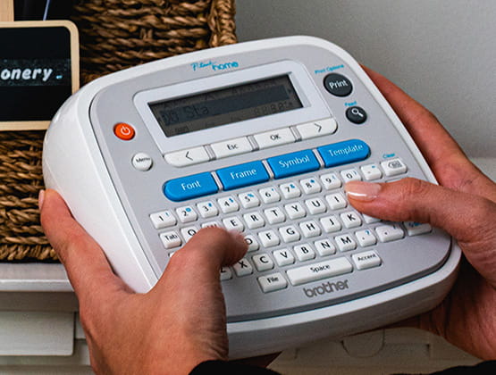 Brother Ptouch displayed hands holding and typing on its built in keyboard