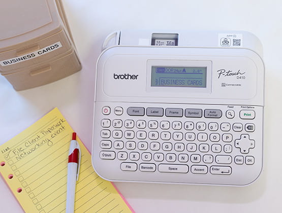 Brother Ptouch Label Maker top view, notebook and a box on the side