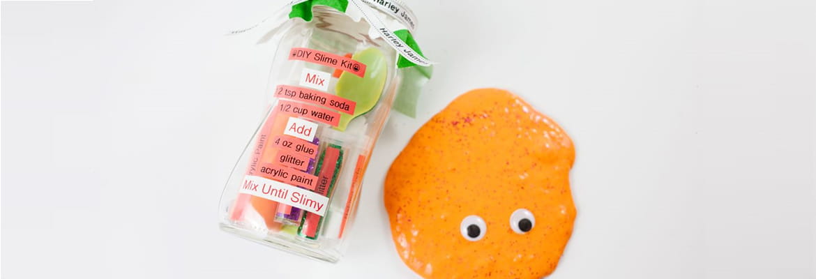 Slime kit jar made with P-touch embellish and orange slime and googly eyes to the right on a blank background 