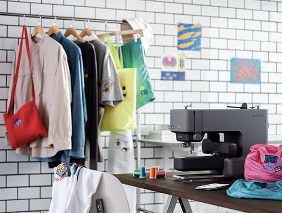 Skitch Embroidery Machine sitting next to some clothes that have been embroidered by Skitch using Artspira