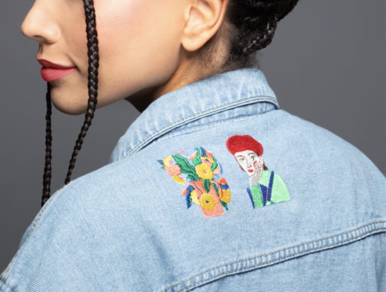 Girl with a denim jacket with embroidered patches on it, embroidered by Skitch