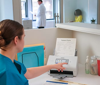 Dentist checking her Brother printer at desk
