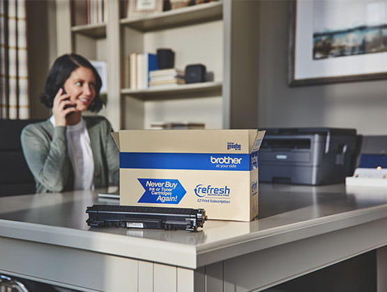 Brother Refresh subscription box, toner cartridge and printer on desk. 