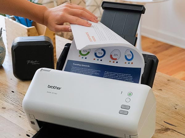 Person putting large stack of full color double-sided documents in scanner's automatic document feed