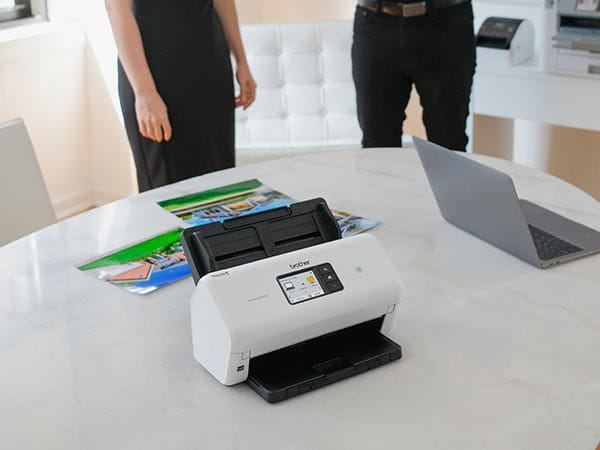 Scanner on conference room table at real estate office with home photos and one-sheets
