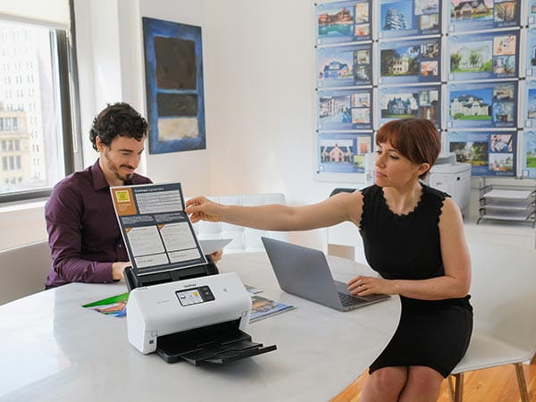 Man and woman in real estate office scanning one-sheets