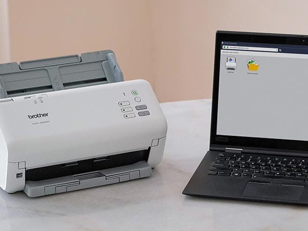 Scanner on office desk with laptop computer showing scan software