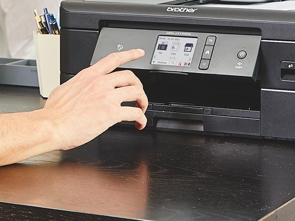 Person using printer's touchscreen to manage device