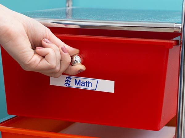 Teacher opening classroom drawer with label reading 