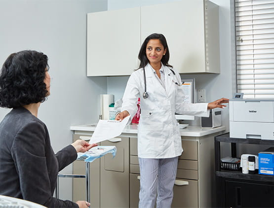 Doctor printing paperwork on Brother printer in exam room