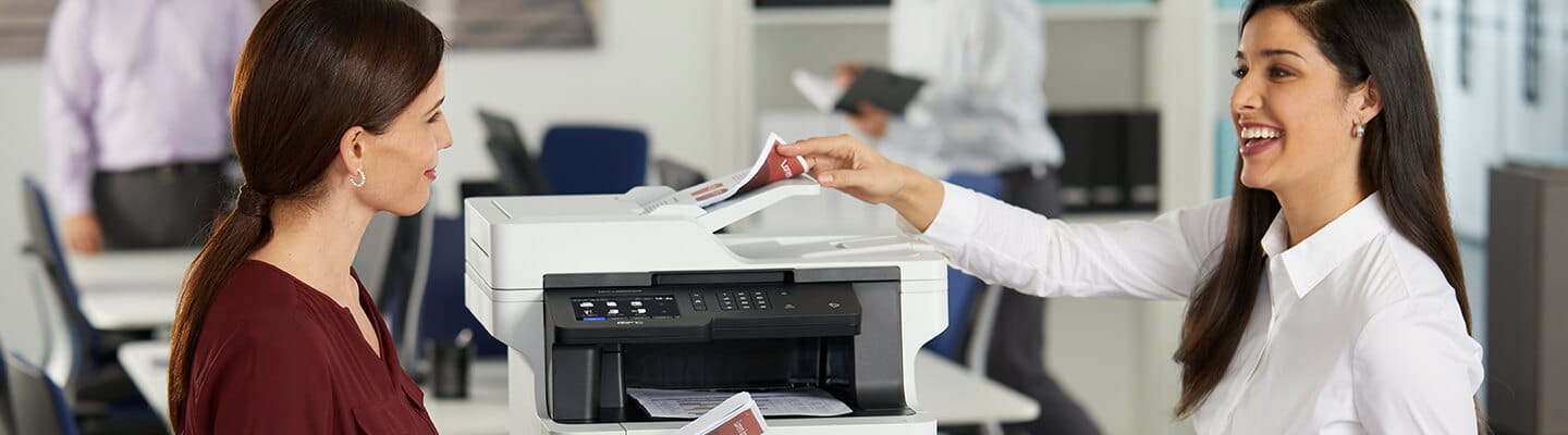 Women standing by MFC-L8895CDW printer in office