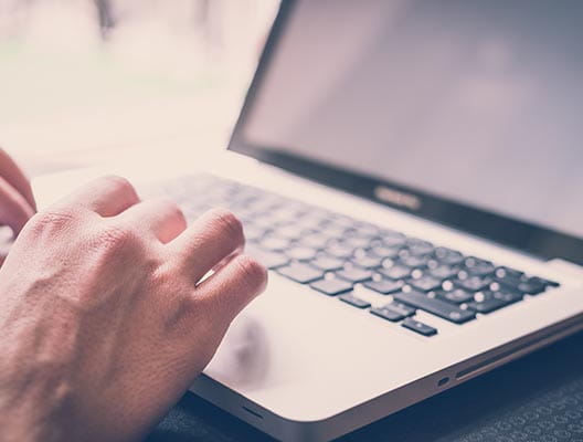 Close up of man typing on a laptop