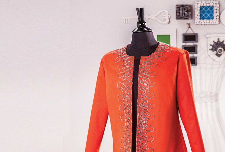 Embellished orange shirt displayed on mannequin