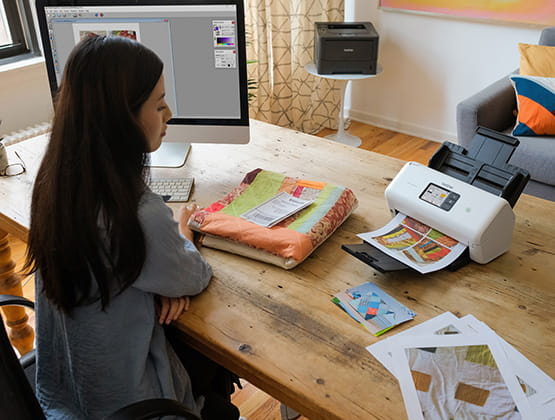 Woman at desk with computer screen and Brother scanner