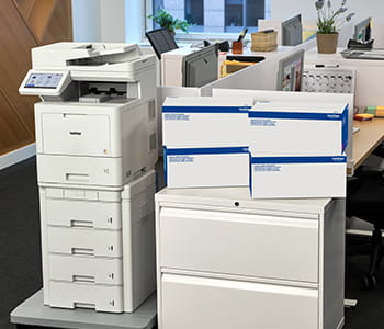 Brother MFC-L9670 in an office setting next to boxes of Brother TN810XL genuine toner