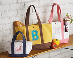 Embroidered hand bags on wooden table against a white brick wall