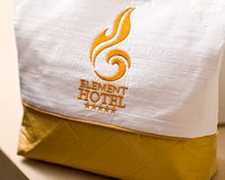 White linen embroidered with "Element Hotel" text in gold thread