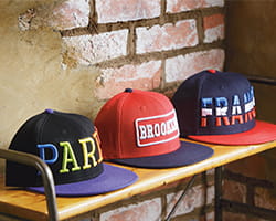 Multi-colored flat brimmed hats on wooden table against brick wall
