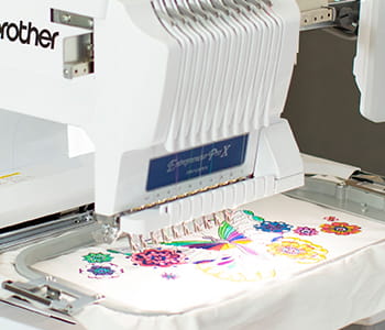 Embroidery machine stitching a floral pattern on white fabric
