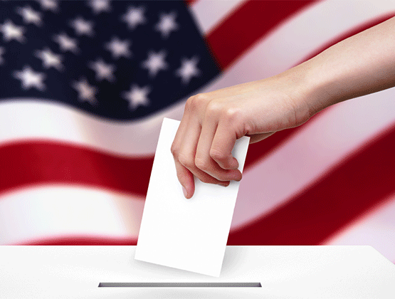 Hand placing voting ballot in box with American flag in background