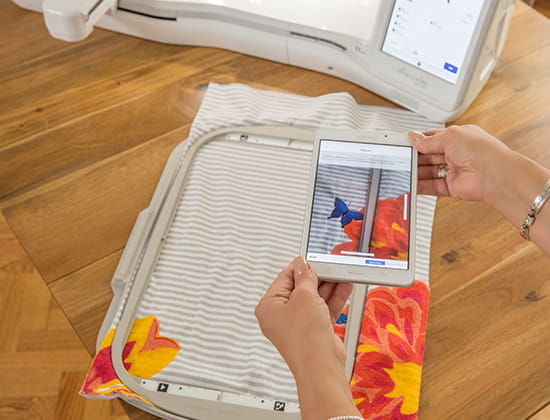 Person using a mobile phone with the My Design Snap mobile app taking a picture of fabric in a hoop