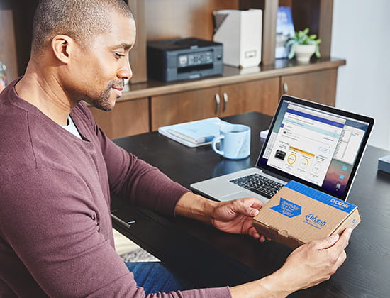 Man sitting at desk with laptop, holding Refresh subscription box