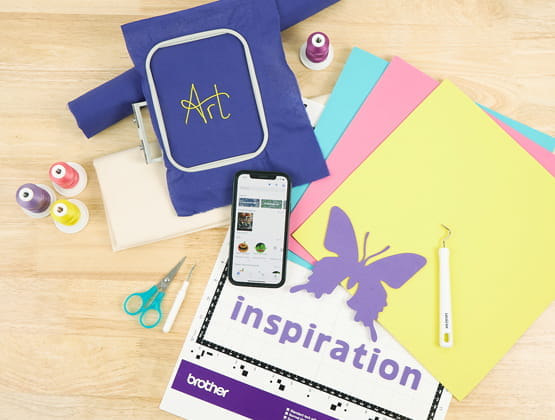 Craft supplies surrounding phone with open Artspira app on table