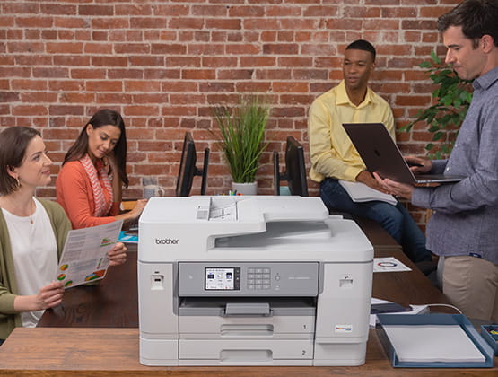 Brother Inkjet printer in foreground with employees talking in background